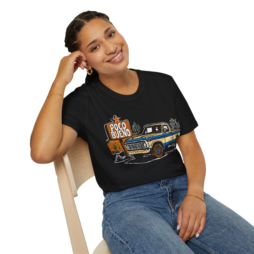 Woman wearing a black t-shirt with a pickup truck graphic design and "Poco Bueno" desert road sign sitting on a chair.